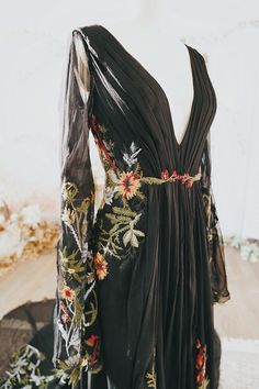 a black dress with flowers and leaves on it