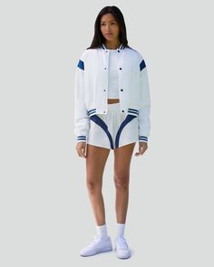 Designed in a cropped silhouette, this bomber jacket is modeled after classic varsity styles. It's made from Taslon, a breathable and resistant tech fabric, with contrast inserts at the shoulders, striped ribbed trims, snaps down the front and logo embroidery on the reverse side of the collar. Colorblock detail at shoulders Striped rib trim at neck, sleeve opening, bottom opening Snap front closure Logo embroidery at back neck Taslon 100% Polyester The Cropped Varsity Bomber Jacket is styled wit Luxury Cotton Varsity Jacket In Sporty Style, Luxury Varsity Jacket With Ribbed Cuffs For Sports, Cheap Spring Varsity Jacket With Ribbed Cuffs, Cheap Hooded Varsity Jacket With Ribbed Cuffs, Luxury Casual Varsity Jacket With Ribbed Cuffs, Cheap Varsity Jacket With Ribbed Cuffs For Sports, Shorts And Jacket Outfit, Windbreaker Shorts, Vintage Windbreaker Jacket