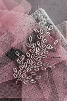 a pink tulle with white flowers and leaves on the top is seen in this close up photo