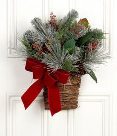 a basket filled with greenery sitting on top of a white door sill next to a red bow