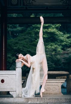 a woman in a white dress is doing a hand stand with her legs stretched out