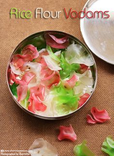 a metal bowl filled with flowers on top of a brown table next to a white plate