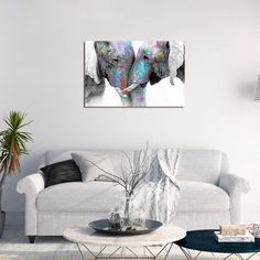 two elephants standing next to each other in a living room with white walls and flooring