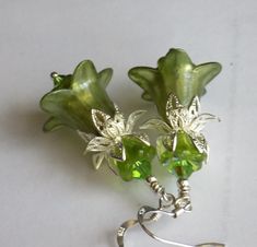 "SHIIMMERING GREEN" New to English Vintage Design! These are my smaller bellflower earrings, for those of you who like something a little daintier. They have all been hand painted in shimmering pearlescent summery colours and feature lovely silver filigree double bead caps, Czech glass beads and flowers, Swarovski Crystals, and sterling silver hooks. As always, they are very lightweight to wear. Shimmering Green, is hand painted in pearly light green with a little matching Czech Glass flower ins Elegant Green Flower Earrings Nickel Free, Green Drop Flower Earrings, Green Flower-shaped Pierced Earrings, Green Flower Drop Earrings, Green Dangle Flower Earrings For Gift, Green Flower Shaped Earrings Gift, Green Flower-shaped Earrings As Gift, Green Flower Shaped Earrings As Gift, Green Flower Earrings As Gift