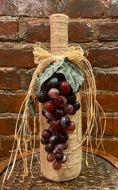 a bottle filled with grapes sitting on top of a table next to a brick wall