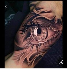 an eye tattoo on the side of a man's leg, with long eyelashes