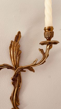 a wall mounted candle holder with a single candle in it's center and an ornately decorated cross on the side