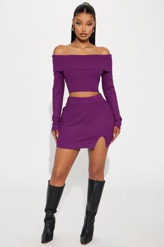 a woman wearing a purple dress and thigh high boots, standing in front of a white background