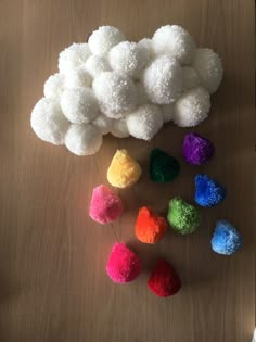 there are many different colored pom poms on the wooden table, and one is white