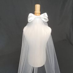 Simple one-tier cut-edge veil with added 6 inch satin bow, ideal for first communion or bachelorette.  Tulle is 54 inches wide so the veil is suitable for children or adults. Length is 20 inches. *This is a petite veil, primarily intended for communion. On an adult, the length is just below the shoulder. Shown on a child's body form. The veil is attached to a clear comb. I can accommodate customizations such as different lengths, embellishments, or barrettes with a slightly extended production t First Communion Tulle Dress With Satin Bow, Tulle First Communion Dress With Satin Bow, White Tulle First Communion Dress With Bow, First Communion Satin Dress With Satin Bow, Satin First Communion Dress With Satin Bow, Elegant White First Communion Dress With Satin Bow, White First Communion Dress With Satin Bow For Party, Elegant Fitted First Communion Dress With Satin Bow, Elegant First Communion Dress With Tulle Bow