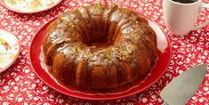 a bundt cake sitting on top of a red plate next to a cup of coffee