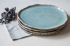 four blue plates stacked on top of each other next to a cloth napkin and flower