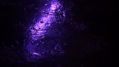 purple light shining down on the ground in the dark