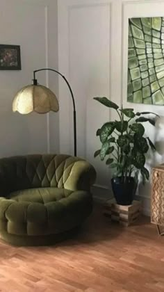 a living room with a green chair next to a lamp and a potted plant