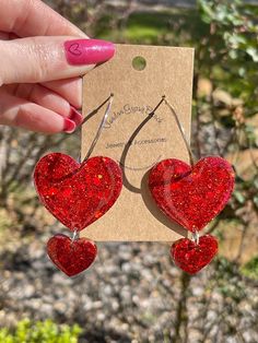 Introducing our best-selling glitter and resin earrings that are simply heart-stopping! Featuring one large and one small heart hanging delicately from a hoop earring, these beauties are perfect for spreading love and sparkle wherever you go. Whether you're celebrating Valentine's Day, rocking out at a concert, or just showing off your love for hearts, these earrings are the ideal accessory. The combination of sizes adds a playful touch to the design, making them a versatile addition to any outfit. Lightweight and comfortable to wear, these earrings are suitable for all-day wear, allowing you to flaunt your love for hearts with ease. So whether you're dancing under the stars or simply embracing your romantic side, these heart hoop earrings are sure to steal the show! Valentine's Day Party Hoop Earrings With Heart Charm, Valentine's Day Party Dangle Hoop Earrings, Valentine's Day Heart Shaped Hoop Earrings For Party, Valentine's Day Heart Hoop Earrings For Party, Glitter Hoop Earrings Gift, Hoop Jewelry With Glitter For Gifts, Hoop Earrings For Valentine's Day Party, Valentine's Day Hoop Earrings For Party, Valentine's Day Sparkling Heart Earrings For Party