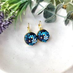 two blue flowers are hanging from gold ear wires