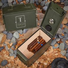 an open box with cigars in it sitting on some wood shavings and rocks