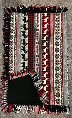 an old blanket is laying on the floor next to a black piece of cloth with red and white designs