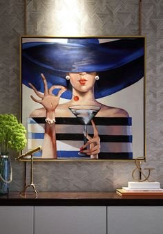 a painting with a woman holding a martini in front of it on a wall above a table