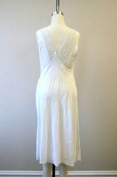 "Description: 1940s pale icy blue-gray night gown (it can look white or it can have a faint gray/blue cast to it). Silky rayon and lace, with a shimmery sheen. Deep V-neckline in the front and back with lace bodice. Gathered bust with a lace waist line. Gathered waist. Condition: In good condition. There is a small dark spot on the bodice, and a couple of tiny holes on the back of the gown. Designer: n/a Stated Size: n/a Measurements: Armpit to armpit: 18.5\" Bodice length: 15\" Overall length: Vintage White Night Dress, White Bias Cut Nightgown For Sleep, Vintage White Nightgown For Wedding Night, Vintage White Wedding Sleepwear, Gown Designer, Blue Building, Women's Nightgowns, Icy Blue, Nightgowns