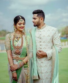 a man and woman standing next to each other in front of a green grass field