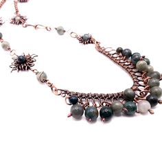 Warm tones of copper pair with varying shades of green moss agate to define this statement necklace. Varying handmade copper links are interspersed with handmade sun charms and are anchored by a beaded frame loaded with moss agate beads. Drop: 15" Frame: 3" across by 3" length Handmade in Lincoln, Nebraska Beaded Frame, Green Moss Agate, Lincoln Nebraska, Copper Frame, Handmade Copper, Agate Beads, Moss Agate, Nebraska, Shades Of Green