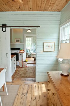 an open kitchen and dining room with wood floors, white walls and wooden ceilinging