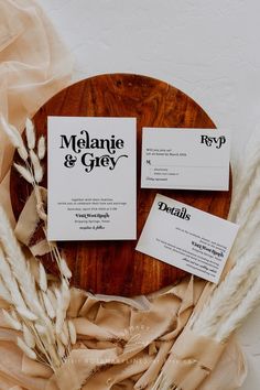 two business cards sitting on top of a wooden plate next to some dried plants and paper