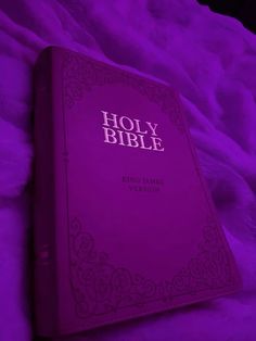 a purple bible laying on top of a bed