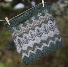 a green and white knitted bag hanging from a clothes line