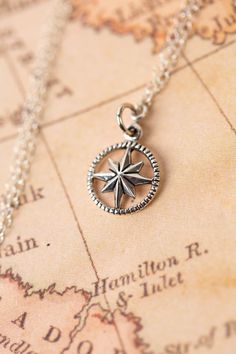 a silver compass necklace on top of a map