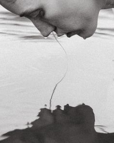 a man is looking down at his reflection in the water