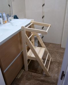 a wooden step stool sitting in front of a bathroom sink