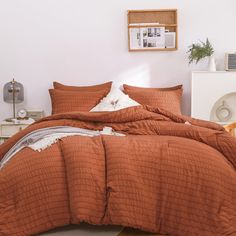 a bed with an orange comforter and pillows