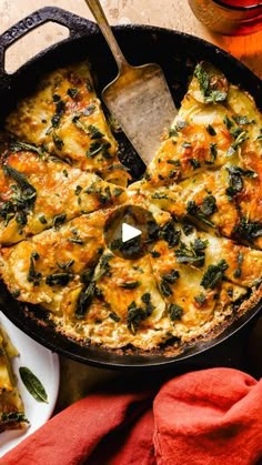 a skillet filled with cheese and spinach on top of a wooden table next to red napkins