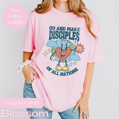 Retro World & Heart Character Bible Verse Christian Unisex Comfort Colors® T-Shirt - Matthew : 28-19 ( With so many color options, if you are struggling to pick one or would like to see one not listed or the design more up-close a color, please reach out and we will check availability or send you some pics. Celebrate the heart and soul of teaching with our beautifully designed Comfort Colors T-Shirt.  Crafted for comfort and style, this tee features a stunning retro world and heart character wit Pink Heart Graphic Short Sleeve T-shirt, Pink Relaxed Fit Slogan Tops, Pink Relaxed Fit Tops With Slogan, Pink Cotton T-shirt With Heart Graphic, Pink Relaxed Fit T-shirt With Slogan, Relaxed Fit Short Sleeve Top With Heart Graphic, Relaxed Fit Crew Neck Shirt With Heart Graphic, Pink Short Sleeve T-shirt With Heart Graphic, Pink Short Sleeve Top With Heart Graphic