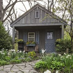 a small house with flowers and plants around it