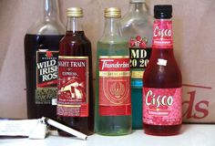 several different types of alcohol sitting on a counter top next to a bag and knife