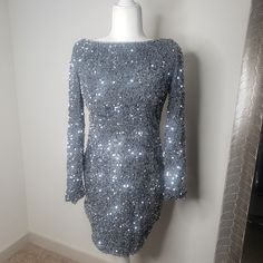 Grey/Silver Sequin Dress Lined Long Sleeves Mini Split In Front Open Back With Tie Invisible Zipper In Back You Will Steal The Show In Our Gorgeous Demure Dress. We Are Obsessed With That Sparkly Sequin Fabric And Open Back Feature. Perfect For A Special Birthday Occasion Or A Night Out With Your Bff's. Team It With Clear Heels For A Super Hot Look. Silver Fitted Long Sleeve Mini Dress, Silver Fitted Long Sleeve Sequin Dress, Silver Sequin Long Sleeve Dress For Night Out, Fitted Long Sleeve Silver Sequin Dress, Silver Long Sleeve Sequin Dress For Night Out, Silver Sequin Long Sleeve Dress For Holiday Party, Silver Long Sleeve Sequin Dress For Party Season, Silver Long Sleeve Sequined Dress, Silver Fitted Sequin Cocktail Dress