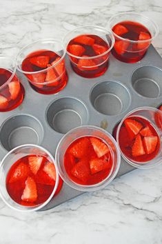 cupcake tins filled with sliced strawberries on top of a marble countertop