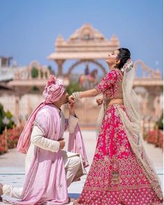 a man kneeling down next to a woman in a pink dress