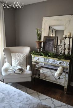 a white chair sitting in front of a mirror on top of a dresser next to a window