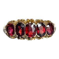 Indulge in the romance of the evening with this exquisite five-stone garnet ring, a captivating piece crafted around 1900 in 18 karat gold. Set with five oval-shaped garnets, each displaying a rich burgundy hue reminiscent of a deep, velvety wine, this ring evokes the warmth and intimacy of a candlelit dinner, where laughter and whispered secrets flow like the finest vintage.  With a total weight of approximately 1.35 carats, the garnets create a striking visual impact that draws the eye and stirs the heart. Measuring 7.6 mm north to south and 18 mm across, this enchanting ring rises 3.6 mm above the finger and narrows gracefully to 1.6 mm at the back of the band. Marked '18ct,' it proudly showcases its English heritage, weighing 4.51 grams and is a size 6.25 US.   Slip this ring onto your Candlelit Dinner, Rich Burgundy, English Heritage, Garnet Ring, Garnet Rings, Gold Set, Antique Victorian, Garnet, 18k Gold