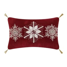 a red and white pillow with snowflakes on the front, along with tassels