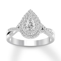 a white gold ring with a pear shaped diamond in the center and pave set shoulders