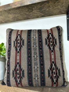 a pillow sitting on top of a wooden shelf next to a potted green plant