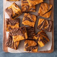 brownie squares with peanut butter swirled on top are sitting on a cutting board, ready to be eaten