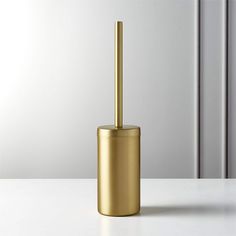 a gold toilet brush holder sitting on top of a white counter