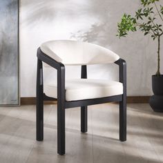 a black and white chair sitting on top of a hard wood floor next to a potted plant