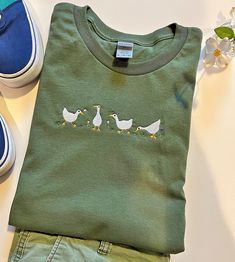 This Geese Embroidered Shirt will make a great gift for the Animal lover in your life. the embroidered design features 4 Geese With Flowers. offering a unique look thats sure to stand out among other casual shirts. Message Me If You Have Any Questions Silly Geese Embroidered Tee | Geese Shirt | Crewneck Aesthetic Tee Shirt | Gift for Goose Lovers | Goose Shirt | Animal Shirt Green Crew Neck T-shirt With Custom Embroidery, Cute Embroidered Cotton Shirt, Casual Long Sleeve Shirt With Embroidered Graphics, Casual Embroidered Long Sleeve T-shirt, Casual Long Sleeve Embroidered T-shirt, Embroidered Green Cotton Shirt, Casual Crew Neck Shirt With Machine Embroidery, Casual Cotton Shirt With Machine Embroidery, Green Long Sleeve T-shirt With Custom Embroidery